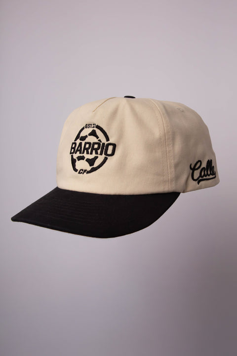 Beige and black cap with 'Barrio Calle' logo on a gray background